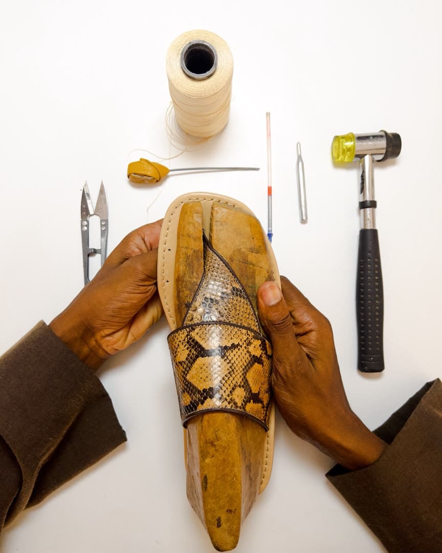 Artisan's hands shaping a python strap over a wooden last